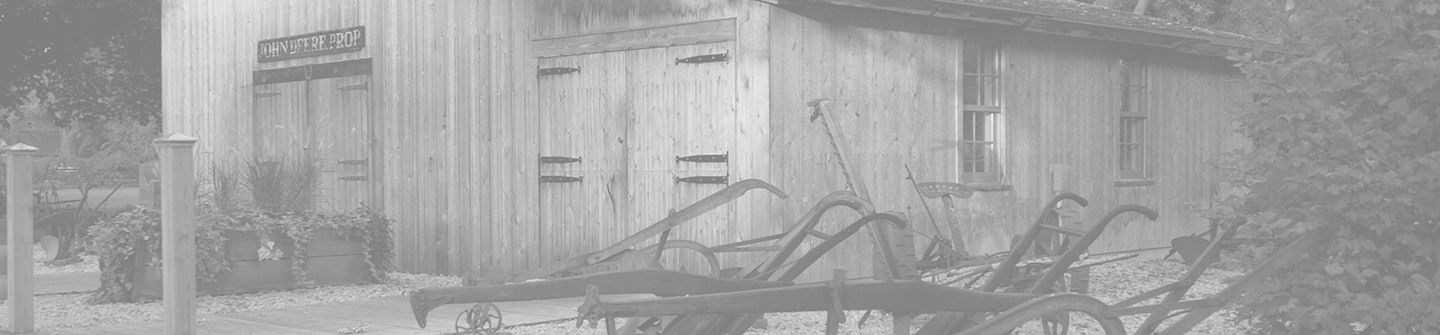 Toned black and white photograph of the Historic Site's recreation of John Deere's original blacksmith shop on a green background
