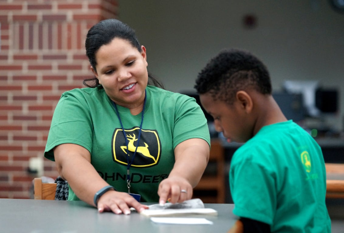 John Deere employee volunteering to assist a student with reading